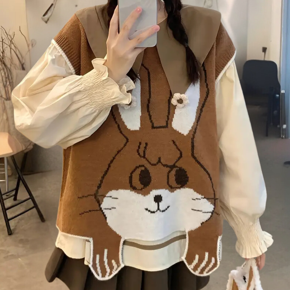 Vrouw in beige blouse en bruine trui met schattig konijnendesign, modieuze herfstkleding, casual outfit, trendy damesmode, selfie in spiegel.