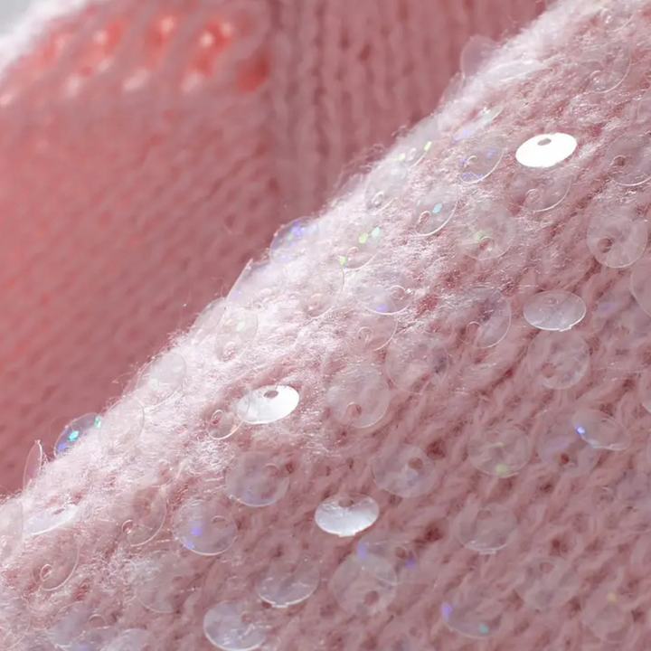 Roze gebreide stof met glinsterende pailletten, close-up. Perfect voor mode, textielontwerp en handwerk. Zachte textuur, trendy uitstraling.
