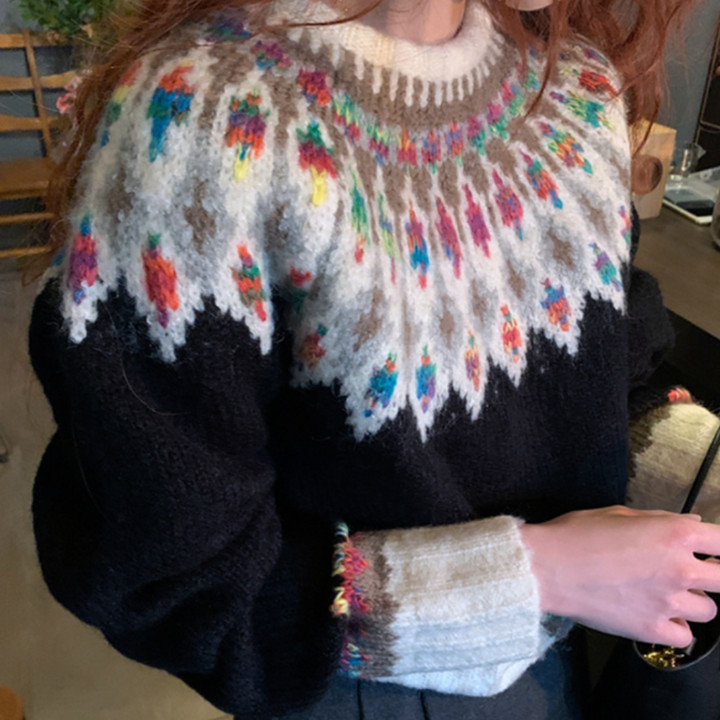 Vrouw draagt een zwarte trui met kleurrijk Noors breipatroon, ideaal voor wintermode. Warme wollen kleding, Scandinavisch design, trendy outfit.