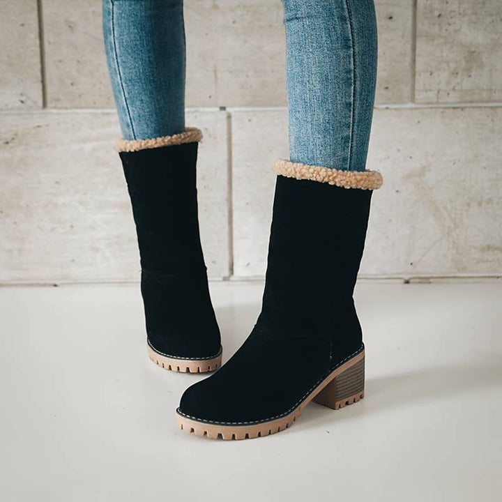 Zwarte suède laarzen met beige voering, gedragen door model in blauwe jeans. Stijlvolle winterlaarzen, comfortabele hak, trendy damesmode.