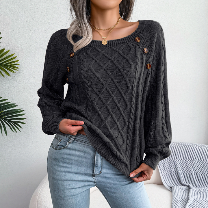 Vrouw draagt zwarte kabeltrui met knopen, gecombineerd met lichtblauwe jeans. Stijlvolle herfstmode, casual outfit, comfortabele dameskleding.