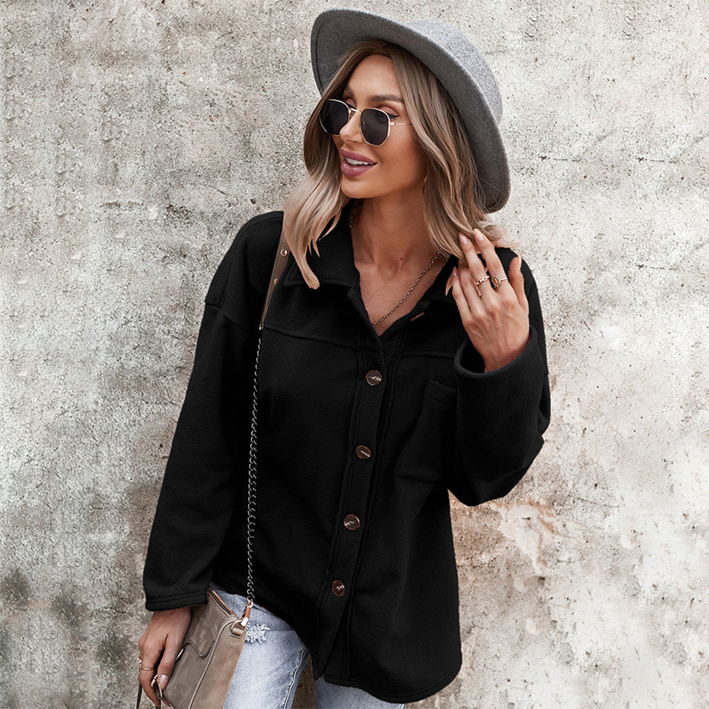 Vrouw in zwarte jas met knopen, grijze hoed en zonnebril tegen betonnen muur. Modieuze herfstkleding, casual stijl, damesmode.