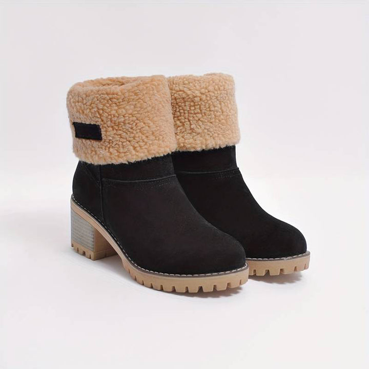 Zwarte dameslaarzen met beige schapenvacht voering, blokhak en rubberen zool. Wintermode, warme schoenen, trendy laarzen voor dames.