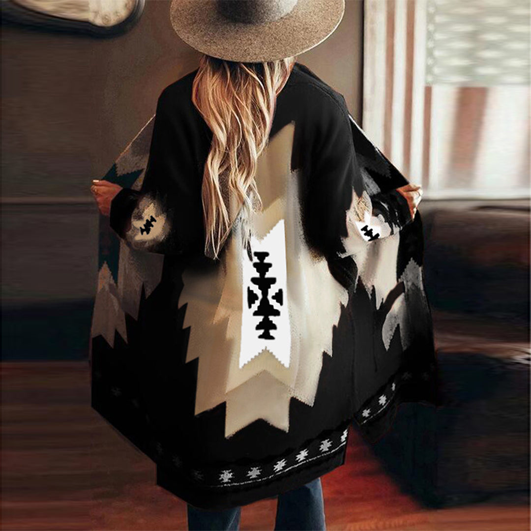 Vrouw in zwarte poncho met Azteekse print, brede hoed, binnenomgeving. Trendy bohemian mode, herfstkleding, etnische stijl.
