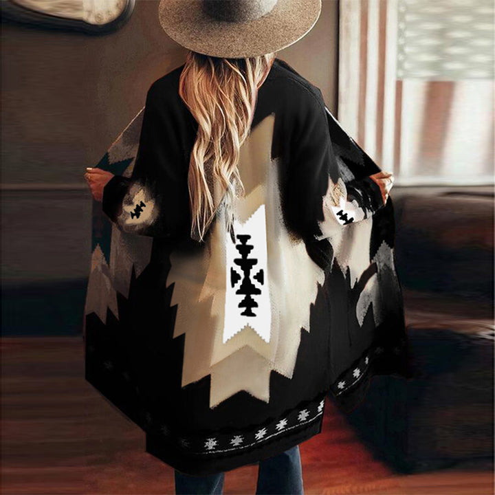 Vrouw in zwarte poncho met Azteekse print, brede hoed, binnenomgeving. Trendy bohemian mode, herfstkleding, etnische stijl.
