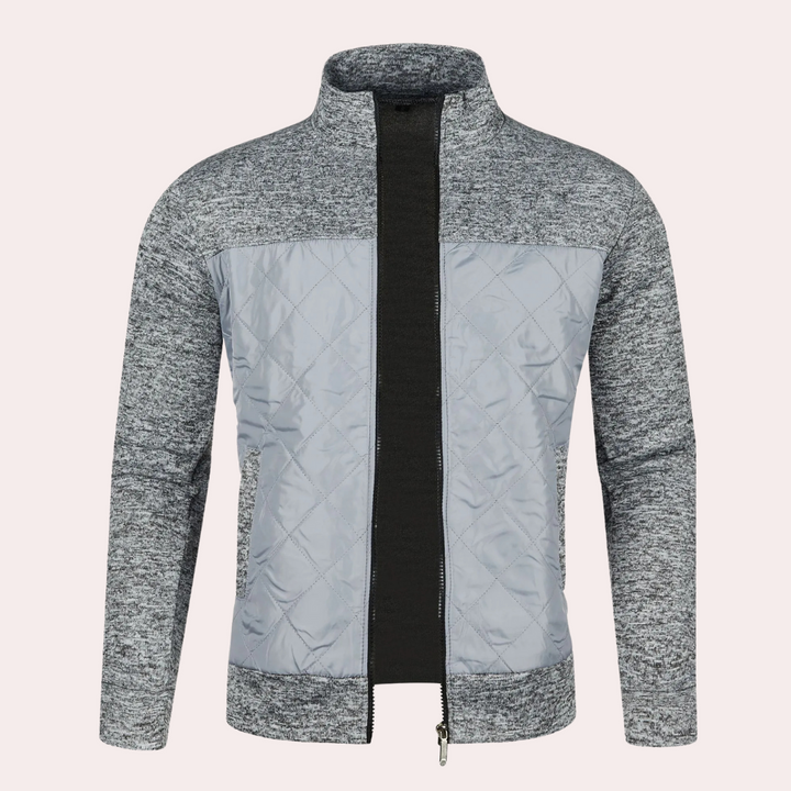 Grijze herenjas met gewatteerde voorzijde en gebreide mouwen, ritssluiting, moderne stijl, ideaal voor herfst en winter, casual en comfortabel.