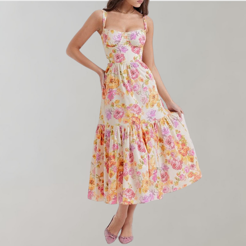 Vrouw in zomerse bloemenjurk met roze en oranje bloemenprint, mouwloos ontwerp, elegante uitstraling, perfect voor casual en feestelijke gelegenheden.