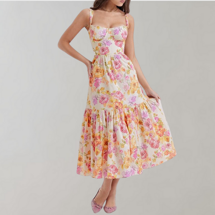 Vrouw in zomerse bloemenjurk met roze en oranje bloemenprint, mouwloos ontwerp, elegante uitstraling, perfect voor casual en feestelijke gelegenheden.