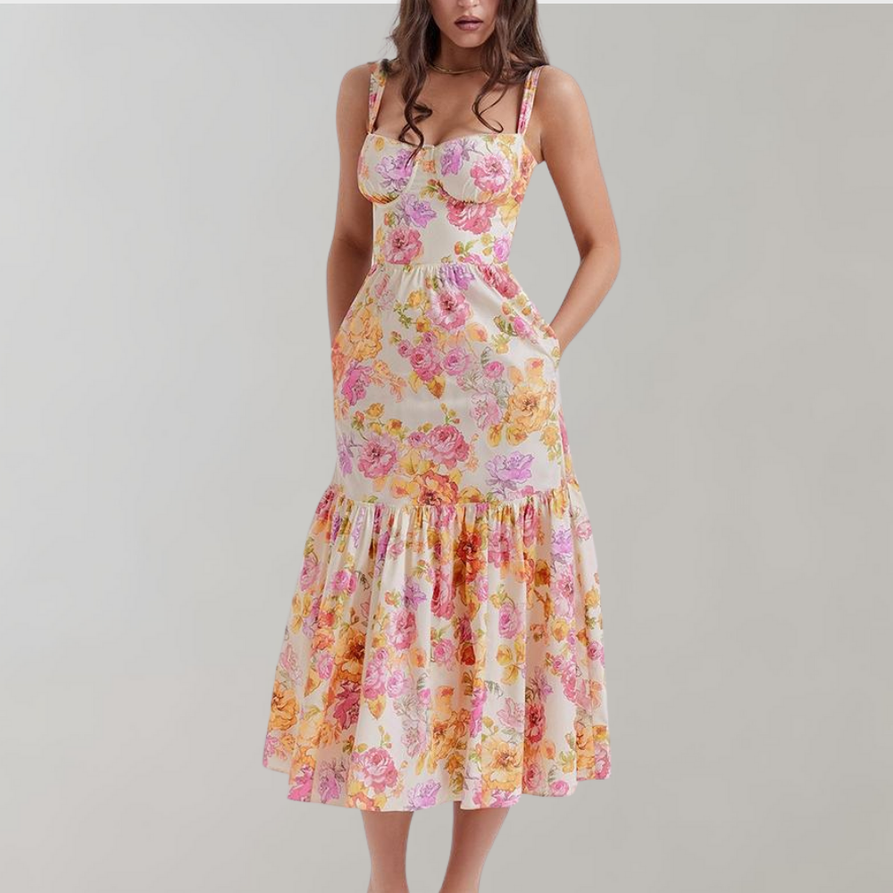 Vrouw in bloemenjurk met roze en gele bloemenprint, mouwloos ontwerp, midi-lengte, zomermode, elegante casual stijl.