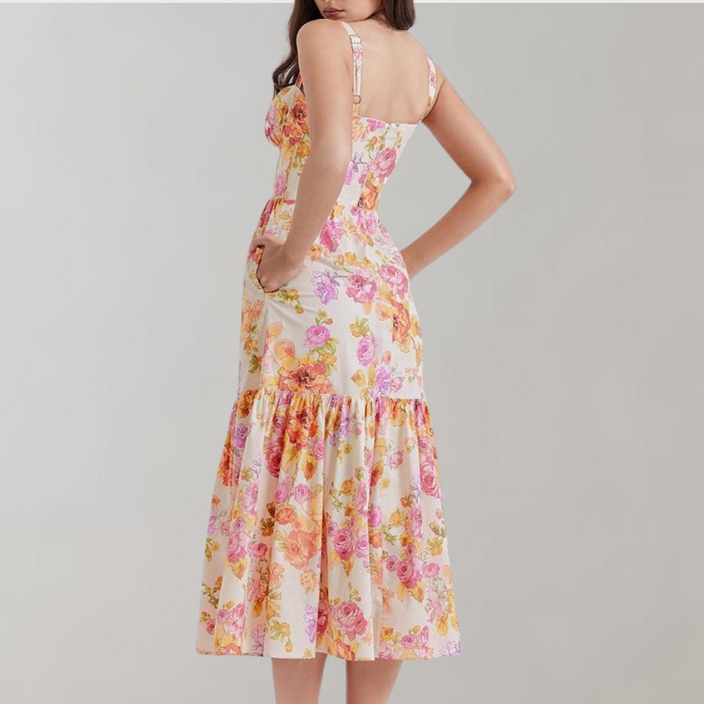 Vrouw in bloemenjurk met roze en gele bloemenprint, mouwloos, midi-lengte, zomermode, elegante dameskleding, rugaanzicht.