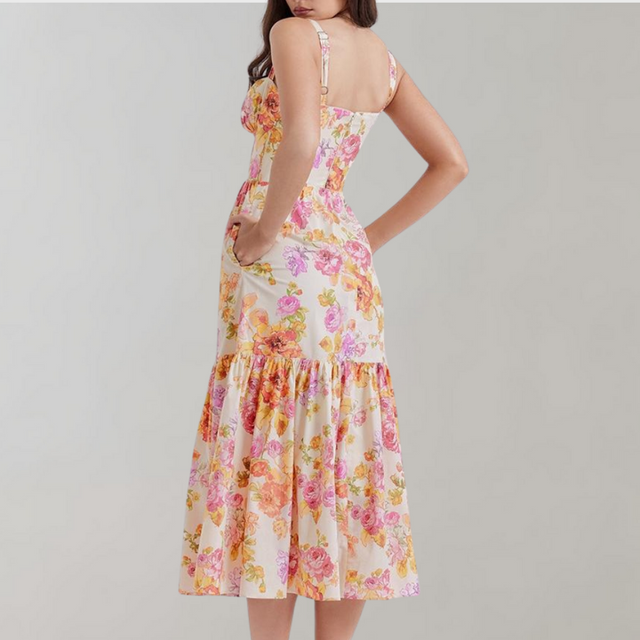 Vrouw in bloemenjurk met roze en gele bloemenprint, mouwloos, midi-lengte, zomermode, elegante dameskleding, rugaanzicht.
