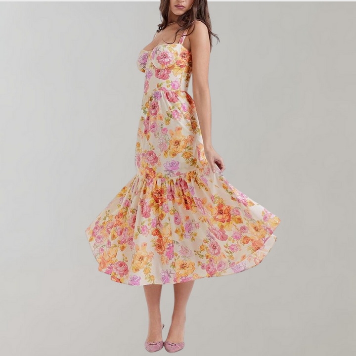 Vrouw in kleurrijke bloemenjurk met roze en oranje bloemenprint, zwierige rok, spaghetti bandjes, modieuze zomeroutfit, elegante stijl.