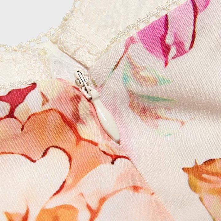 Close-up van een bloemenjurk met rits en kanten details. Elegante roze en beige bloemenprint op zachte stof. Perfect voor zomermode en casual outfits.
