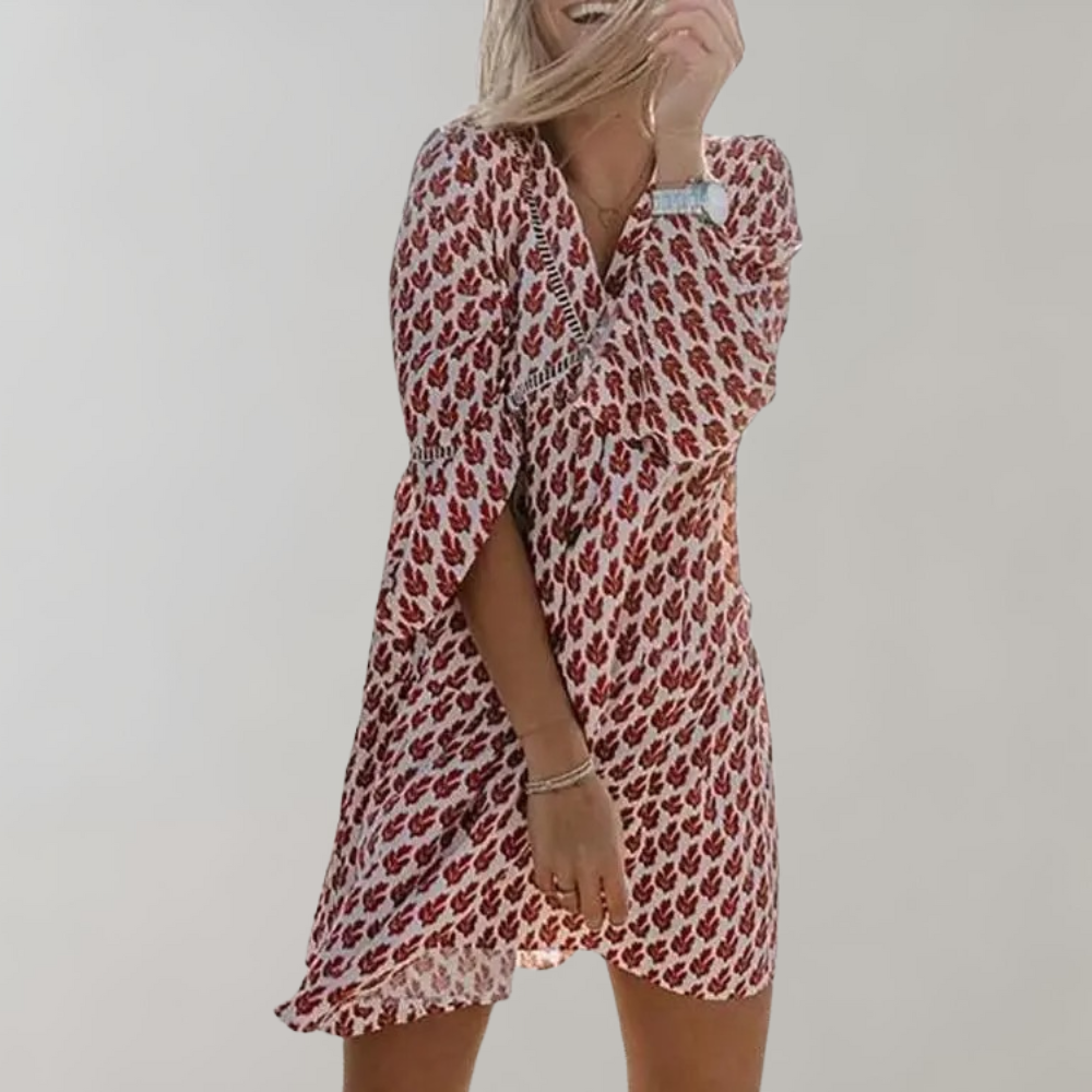 Vrouw in rode bloemenjurk met driekwart mouwen, lachend en poserend tegen een neutrale achtergrond. Trendy damesmode, zomerjurk.