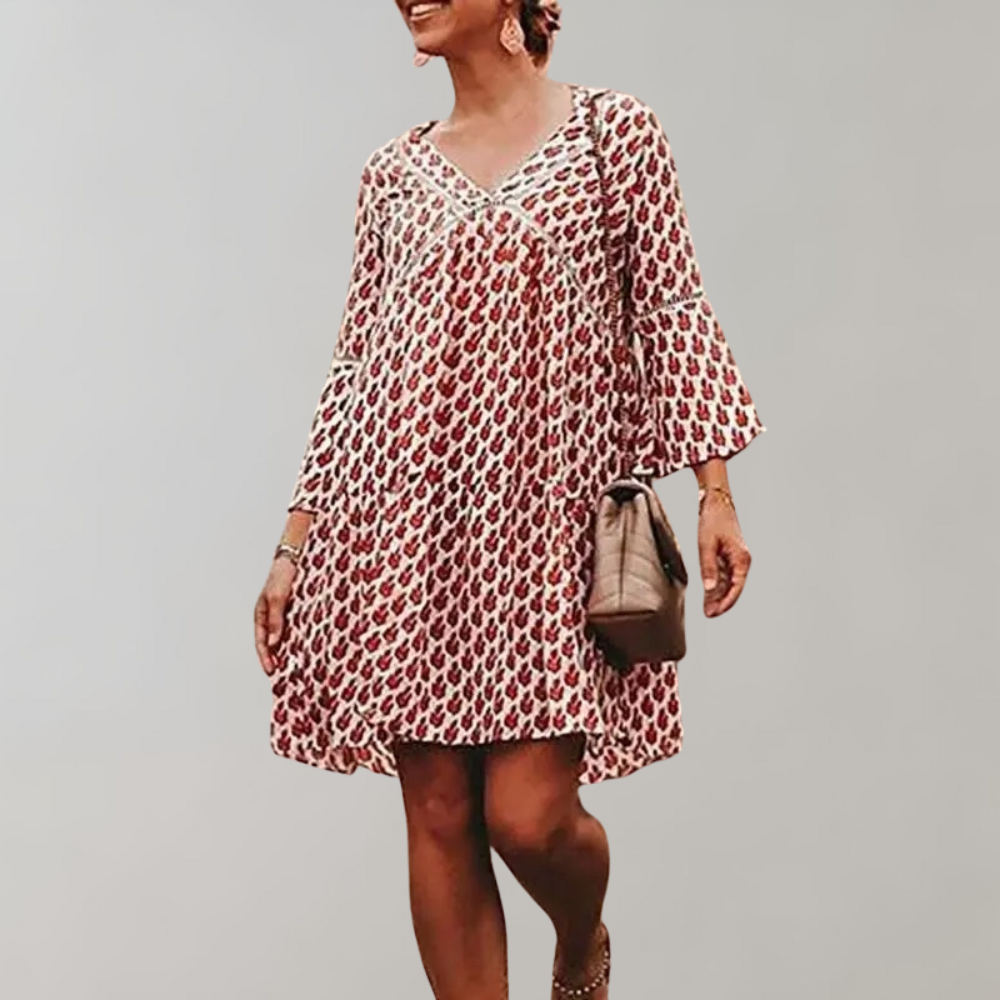 Vrouw in rode bohemian jurk met bloemenprint, driekwart mouwen en V-hals, draagt een beige tas. Perfect voor zomerse casual outfits.