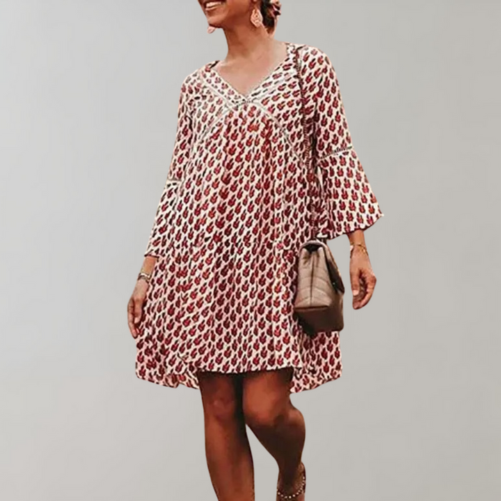 Vrouw in rode bohemian jurk met bloemenprint, driekwart mouwen en V-hals, draagt een beige tas. Perfect voor zomerse casual outfits.