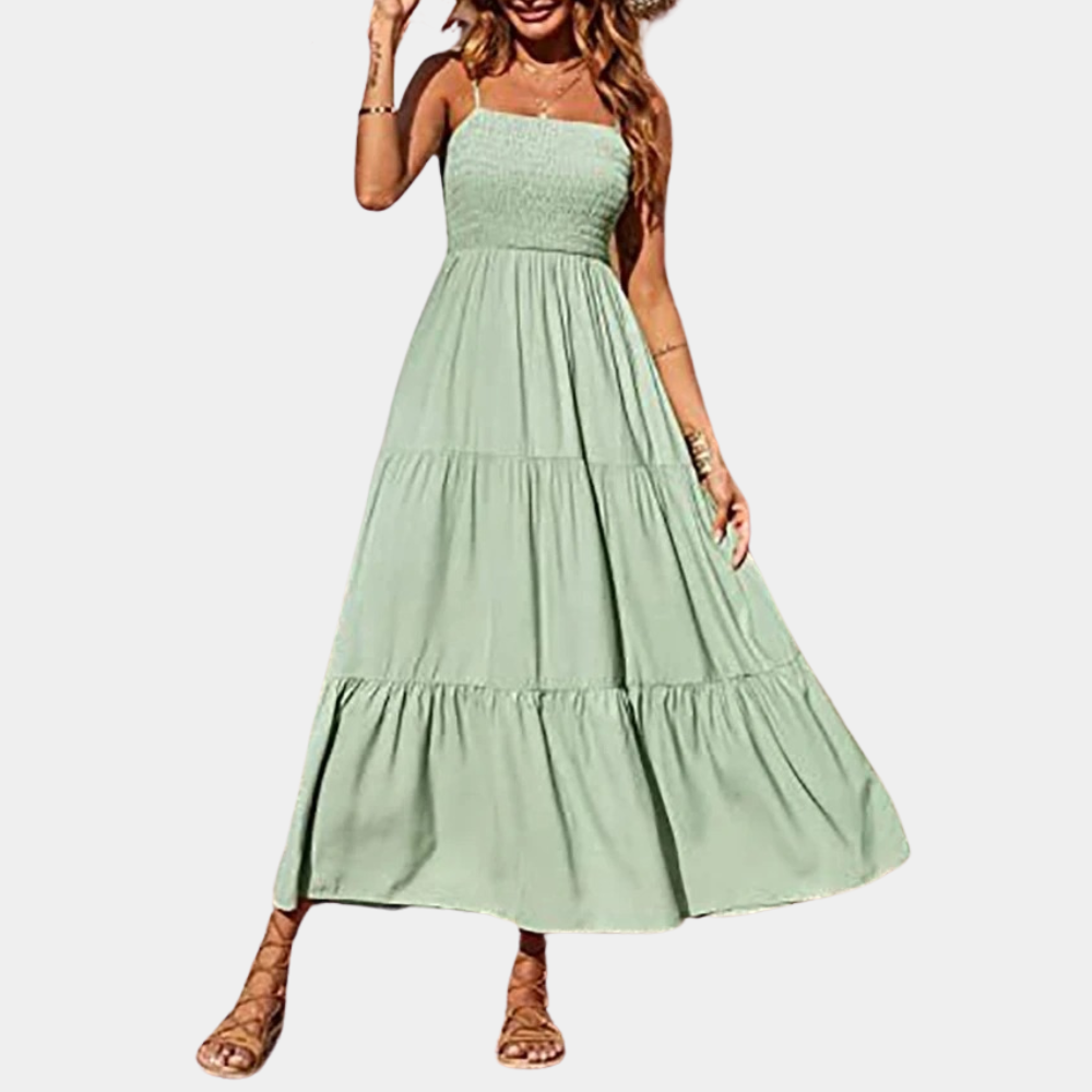 Vrouw in lange groene zomerjurk met gesmokte top en wijde rok, ideaal voor casual en strandkleding. Trendy damesmode, comfortabele pasvorm.