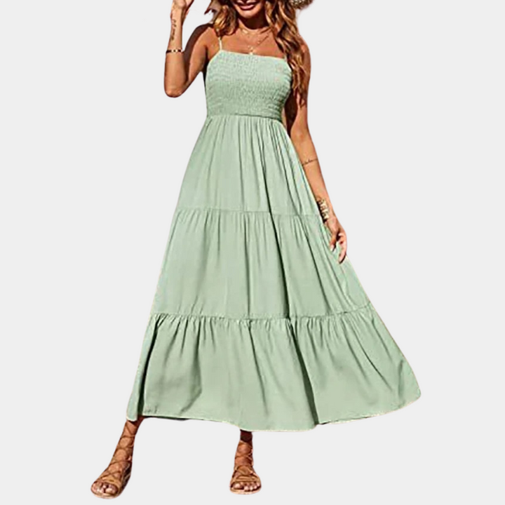 Vrouw in lange groene zomerjurk met gesmokte top en wijde rok, ideaal voor casual en strandkleding. Trendy damesmode, comfortabele pasvorm.