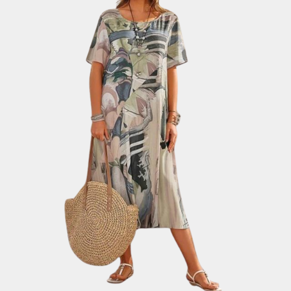 Vrouw in kleurrijke, losse zomerjurk met abstract bloemenpatroon, draagt een grote strooien tas en sandalen. Perfect voor casual zomermode.