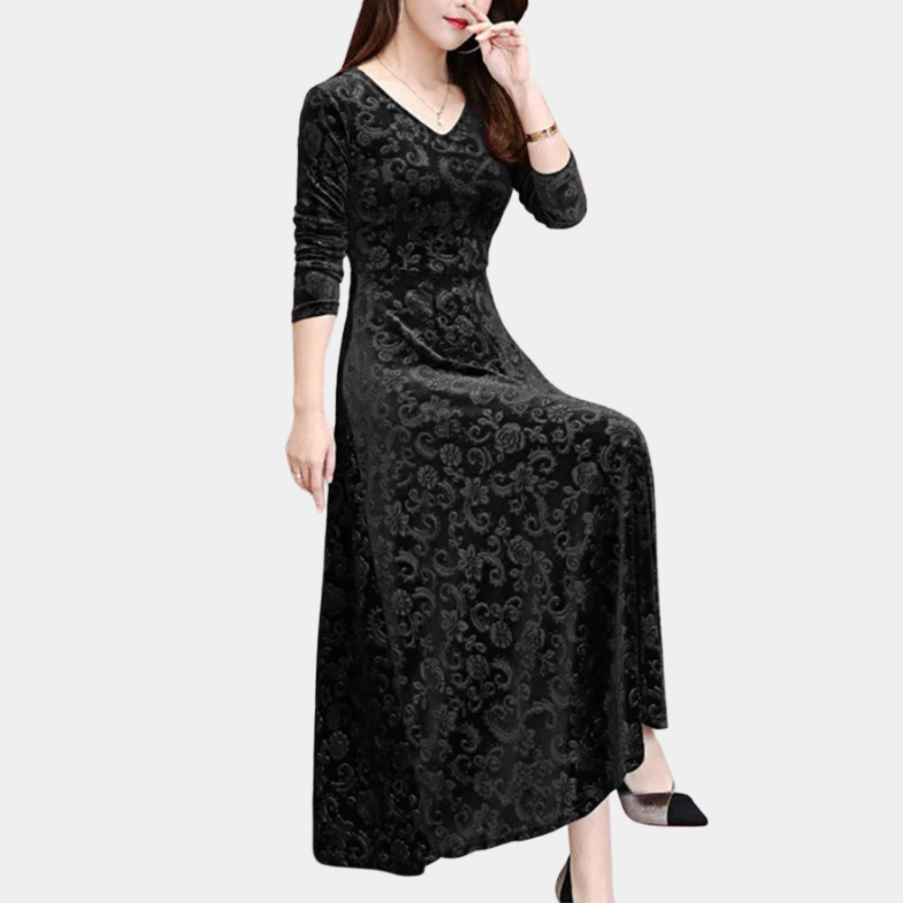 Zwarte fluwelen jurk met lange mouwen en V-hals, elegant patroon, gedragen door zittende vrouw. Perfect voor avondkleding en formele gelegenheden.