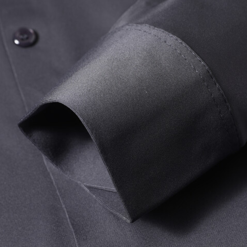 Donkerblauw overhemd met lange mouw, close-up van manchet en knoop. Hoogwaardige stof, elegant design, geschikt voor formele gelegenheden.