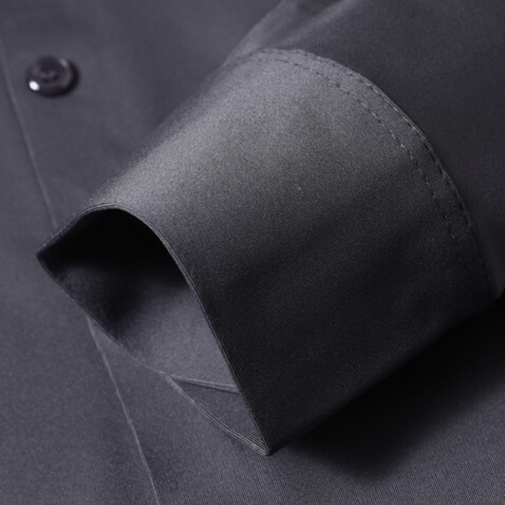 Donkerblauw overhemd met lange mouw, close-up van manchet en knoop. Hoogwaardige stof, elegant design, geschikt voor formele gelegenheden.