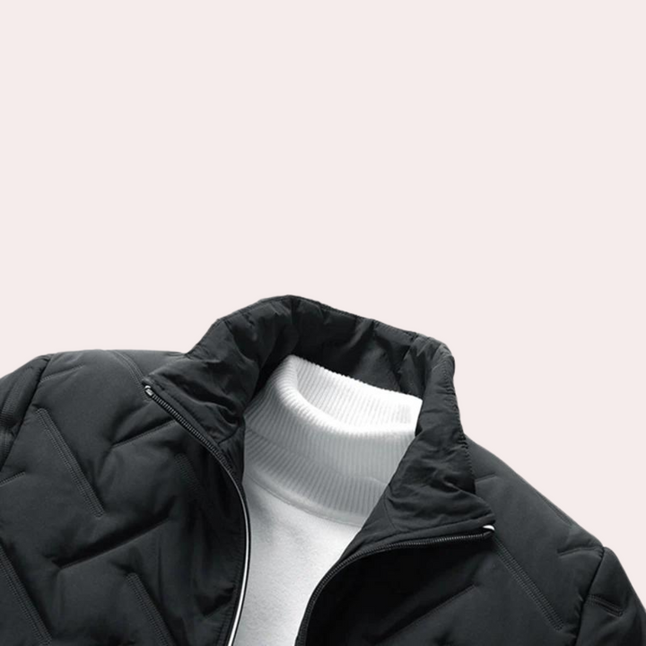 Zwarte gewatteerde jas met opstaande kraag, gedragen over witte trui. Stijlvolle wintermode, herenjas, warme kleding, minimalistisch design.