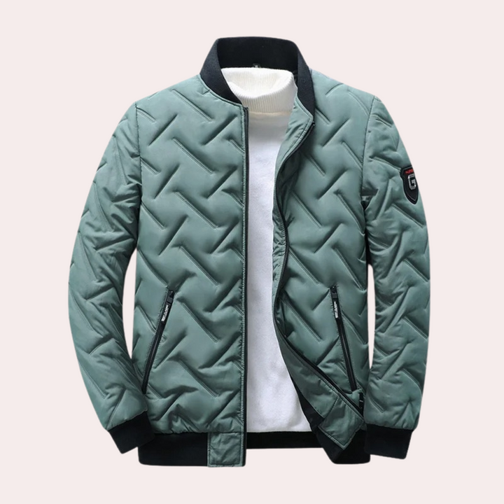 Groene gewatteerde jas met ritssluiting, zwarte kraag en manchetten, en een embleem op de mouw. Stijlvolle winterjas voor heren.