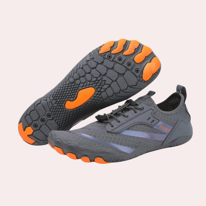 Grijze minimalistische hardloopschoenen met oranje zool, lichtgewicht ontwerp, ademend materiaal, ideaal voor trailrunning en fitnessactiviteiten.