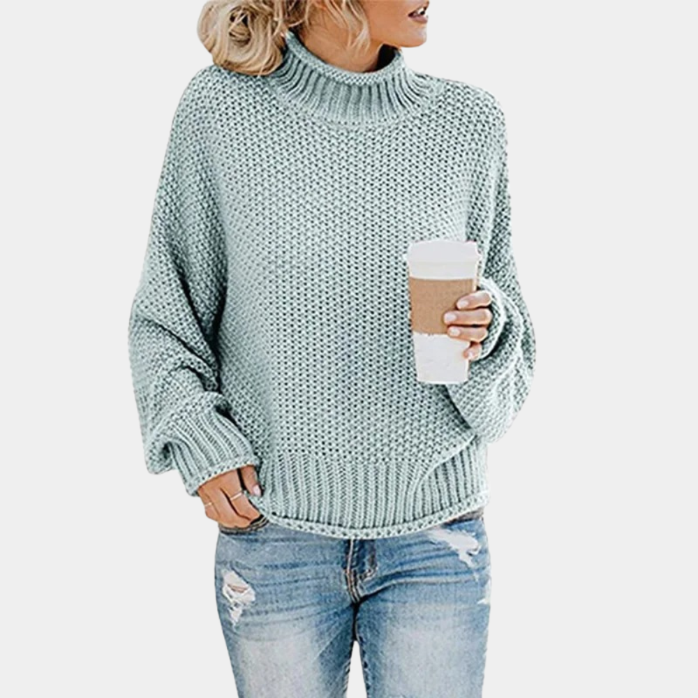 Vrouw in lichtblauwe gebreide trui met opgerolde mouwen, houdt een koffiebeker vast. Casual mode, herfstkleding, comfortabele stijl.