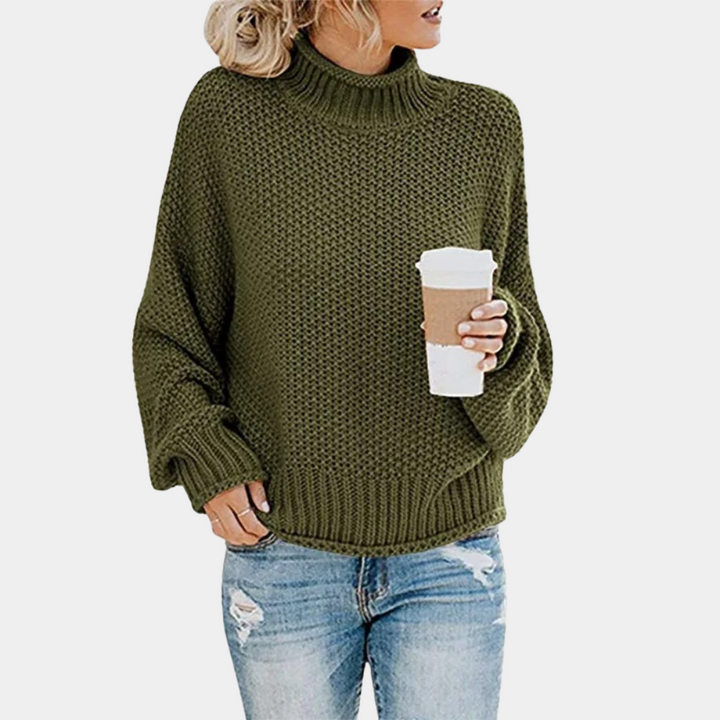 Vrouw in groene gebreide trui met col, houdt een koffiebeker vast. Casual outfit met blauwe spijkerbroek. Modieuze herfstkleding.