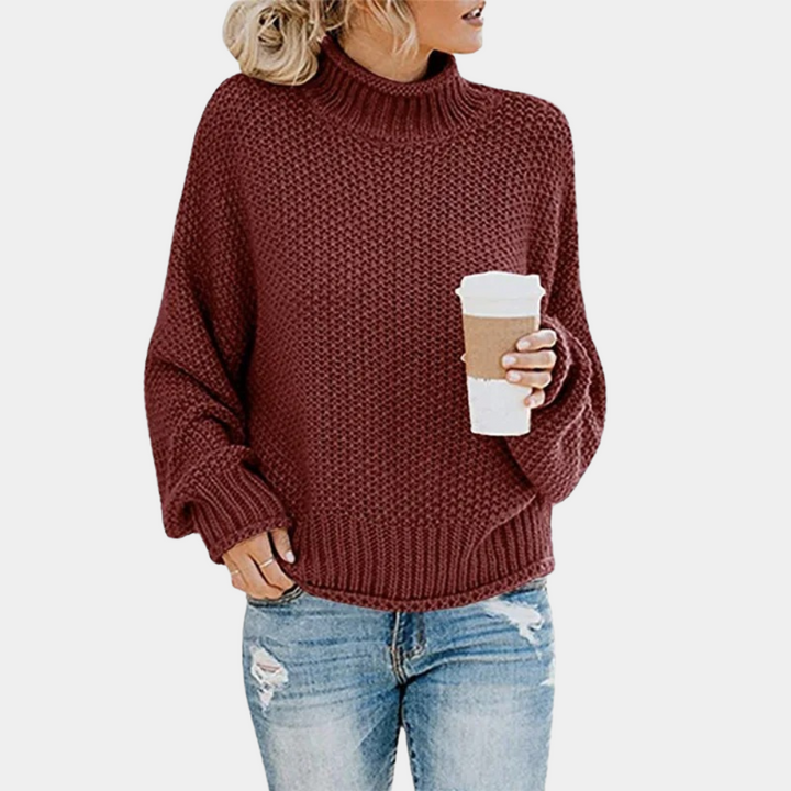 Vrouw in wijnrode gebreide trui met col, houdt een koffiebeker vast. Casual outfit met blauwe spijkerbroek. Herfstmode, comfortabele kledingstijl.