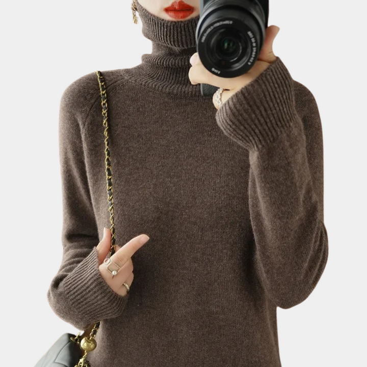 Vrouw in bruine coltrui met camera, gouden kettingtas en sieraden. Modieuze herfstkleding, stijlvolle accessoires, fotografie.
