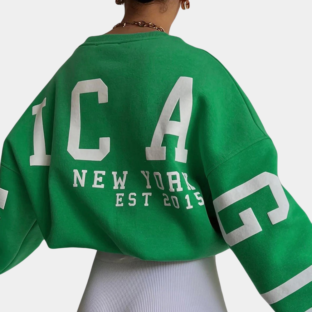 Groene oversized sweater met witte letters "NEW YORK EST 2015" en "ICA", gedragen door een persoon. Trendy streetwear mode, casual stijl.
