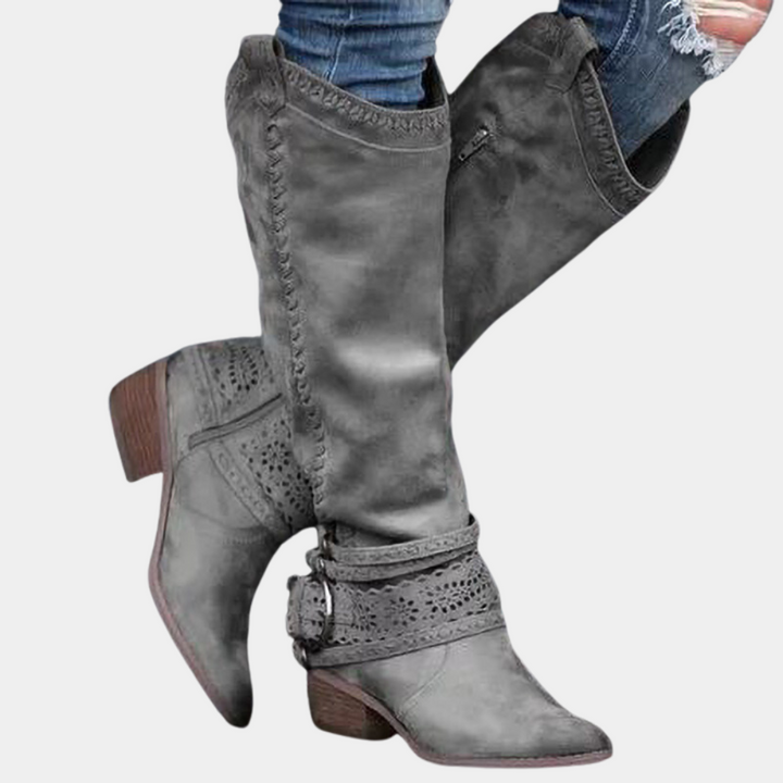 Grijze leren laarzen met hak, decoratieve stiksels en gespen, gedragen met spijkerbroek. Stijlvolle dameslaarzen voor herfstmode.