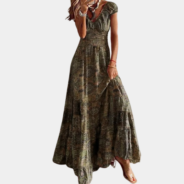 Vrouw in lange, bohemian jurk met paisleyprint, korte mouwen en V-hals. Perfect voor zomer, casual en elegante gelegenheden.