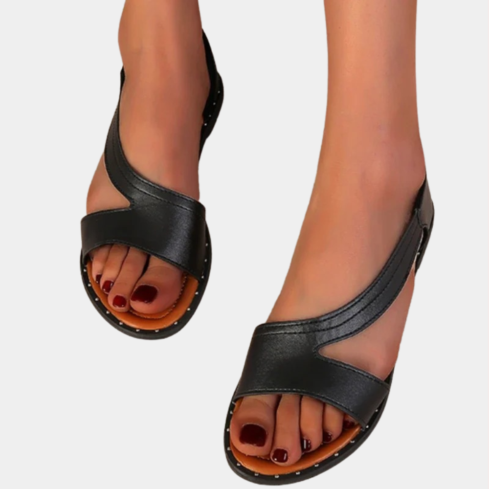 Zwarte leren sandalen met open teen en lage hak, gedragen door een model. Comfortabele zomerschoenen voor dames, ideaal voor casual en elegante outfits.