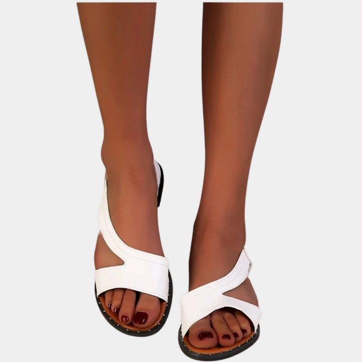 Witte leren sandalen met open teen en kruisbanden, gedragen door vrouw. Stijlvolle zomerschoenen, perfect voor casual en formele gelegenheden.