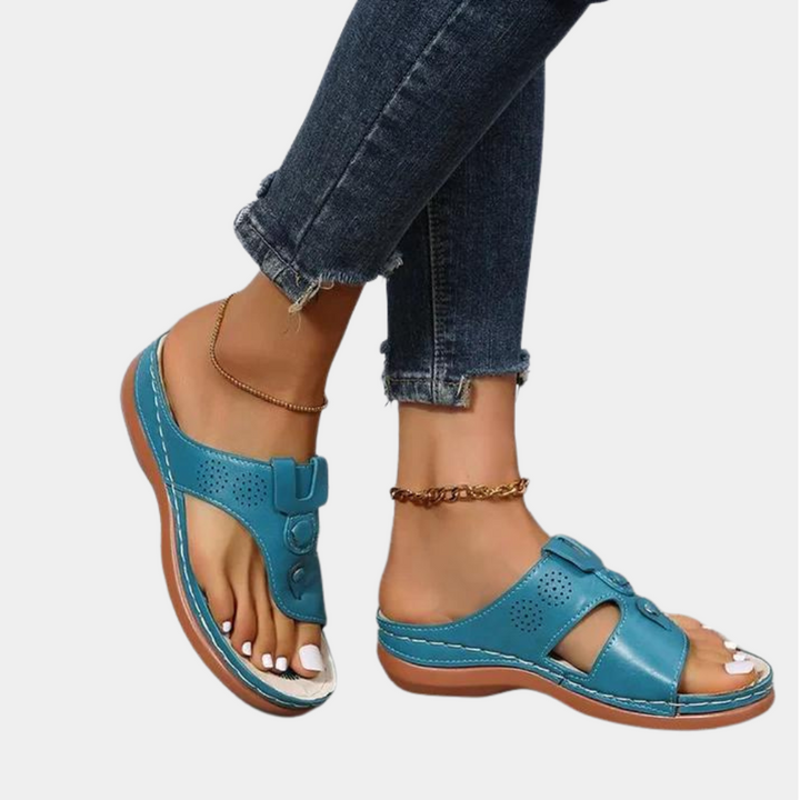 Vrouw draagt blauwe leren sandalen met open teen en verstelbare bandjes, gecombineerd met donkere jeans. Comfortabele zomerschoenen voor dames.