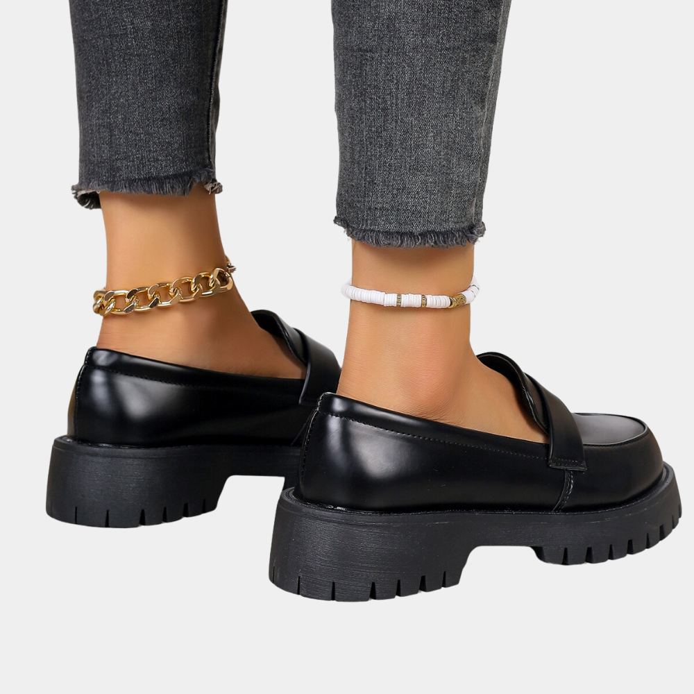 Zwarte leren loafers met dikke zool, gedragen met grijze jeans en gouden enkelband. Modieuze dames schoenen, casual stijl.