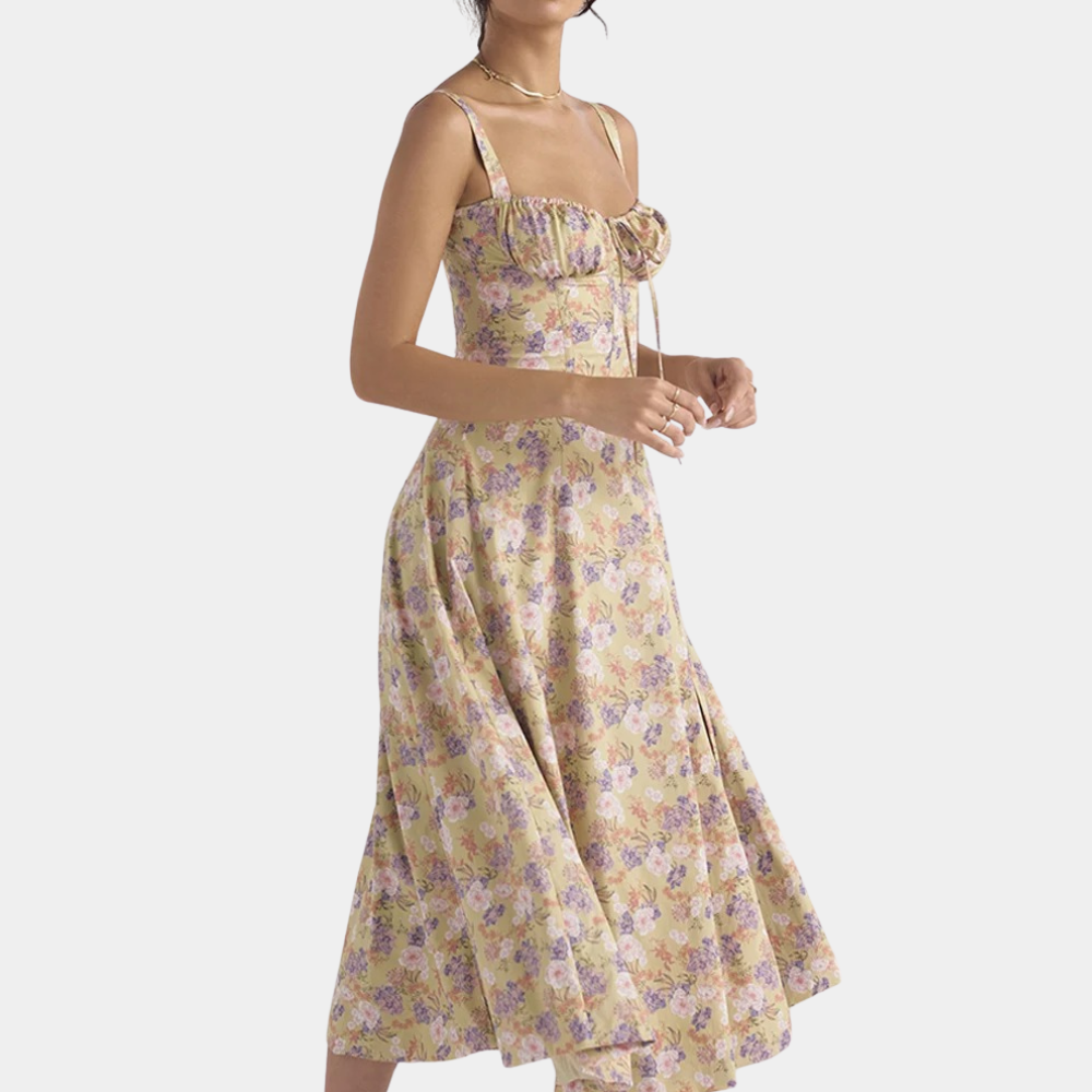 Vrouw in beige bloemenjurk met paarse en roze bloemenprint, mouwloos ontwerp, elegante zomerjurk, casual mode, trendy dameskleding.
