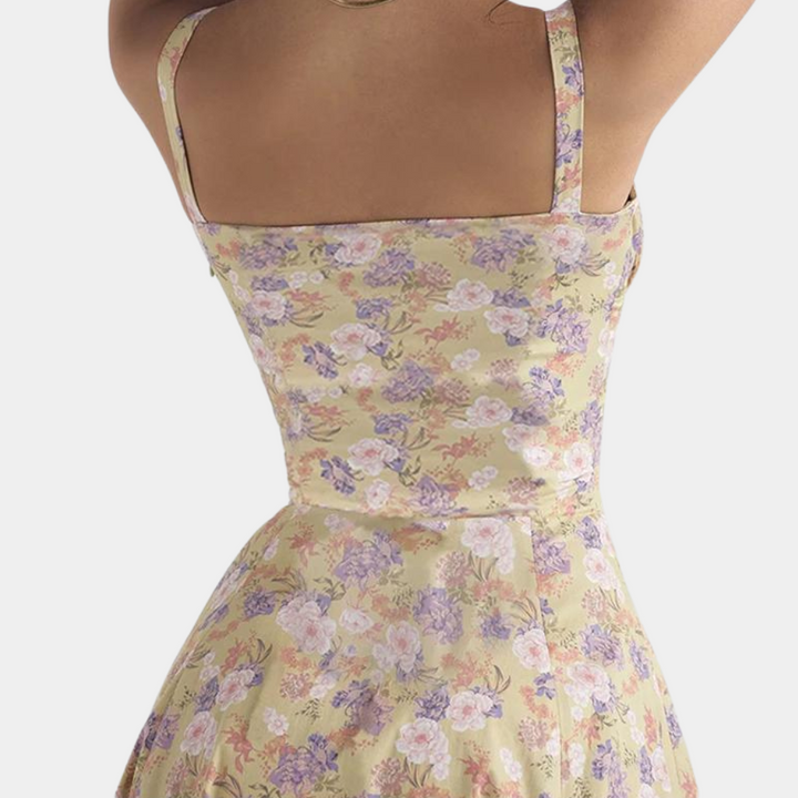 Vrouw in bloemenjurk met pastelkleuren, mouwloos ontwerp, getailleerde pasvorm. Perfect voor zomermode, casual en elegante stijl.