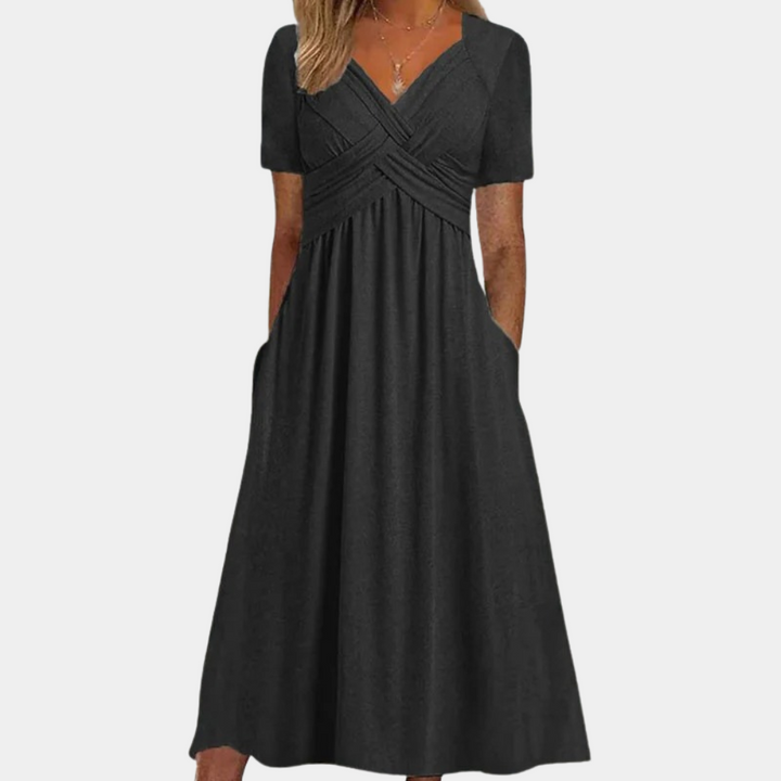 Zwarte midi-jurk met korte mouwen, V-hals en geplooid detail. Elegante damesmode, perfect voor casual en formele gelegenheden.