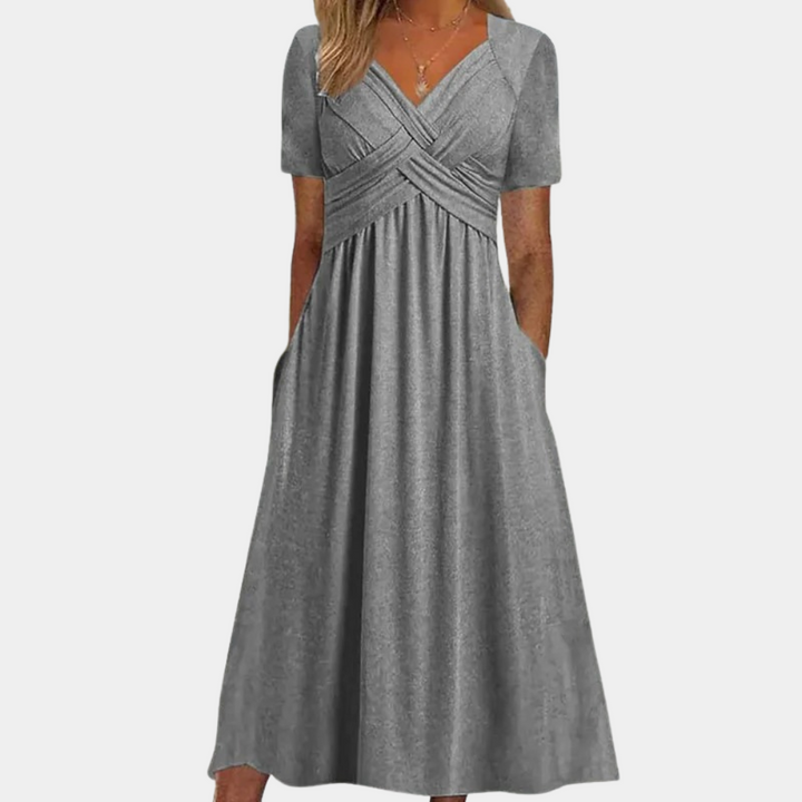 Grijze damesjurk met korte mouwen en V-hals, elegante plooien en zakken. Perfect voor casual en formele gelegenheden. Comfortabele pasvorm.