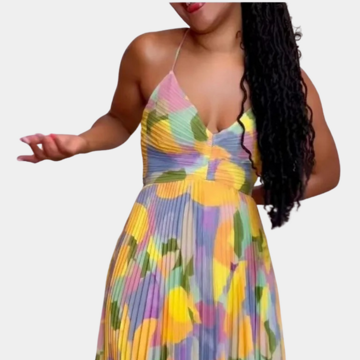 Vrouw in kleurrijke, geplooide zomerjurk met bloemenprint, spaghetti bandjes en V-hals. Perfect voor casual en feestelijke gelegenheden.