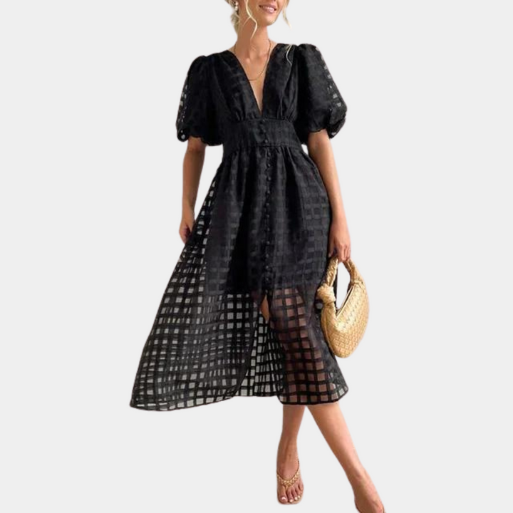 Vrouw in elegante zwarte jurk met pofmouwen en transparant ruitpatroon, draagt een rieten tas en sandalen. Perfect voor zomerse mode.