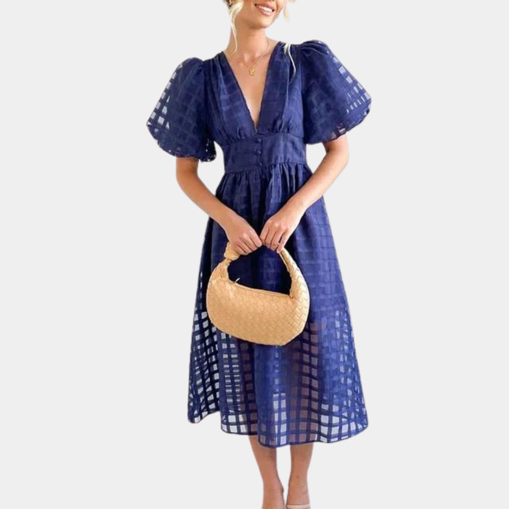 Vrouw in blauwe jurk met pofmouwen en ruitpatroon, houdt een beige handtas vast. Elegante damesmode, zomerjurk, trendy outfit.
