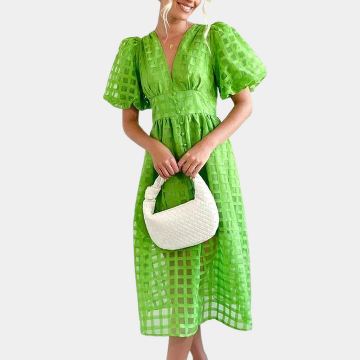 Vrouw in grasgroene jurk met vierkante patronen en pofmouwen, houdt witte gevlochten handtas vast. Trendy zomeroutfit, modieuze dameskleding.