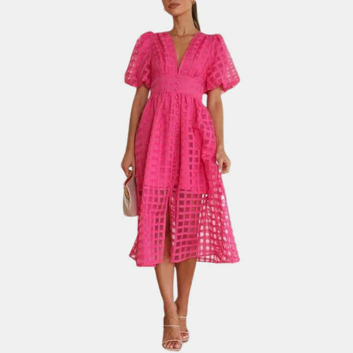 Vrouw in roze midi-jurk met vierkante patronen, korte mouwen en V-hals. Perfect voor zomermode en elegante gelegenheden.