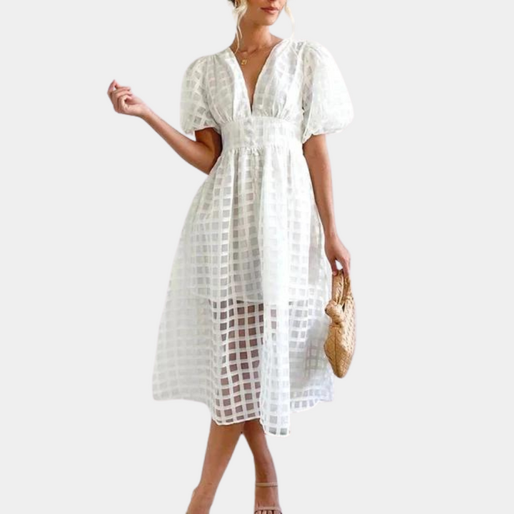 Vrouw in elegante witte jurk met ruitpatroon, pofmouwen en V-hals, draagt een rieten tas. Perfect voor zomermode en casual chique stijl.